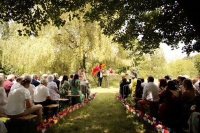 Voiture ancienne bleue décorée de rubans blancs et de fleurs pour une cérémonie, stationnée en extérieur.