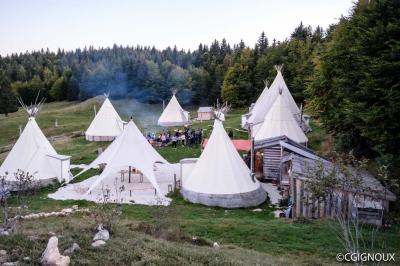 Plat de fromage fondu servi dans des ramequins en terre cuite sur une table en bois, avec du vin rouge et du pain.