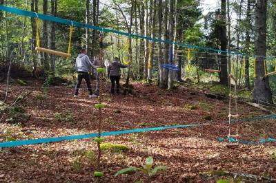 Groupe de personnes rassemblées en extérieur près de tentes et d'une table avec des verres, dans un cadre naturel.