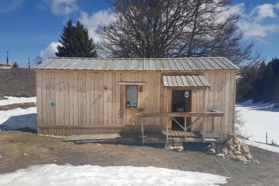 Groupe de personnes rassemblées en extérieur près de tentes et d'une table avec des verres, dans un cadre naturel.