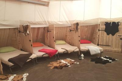 Groupe de personnes rassemblées en extérieur près de tentes et d'une table avec des verres, dans un cadre naturel.