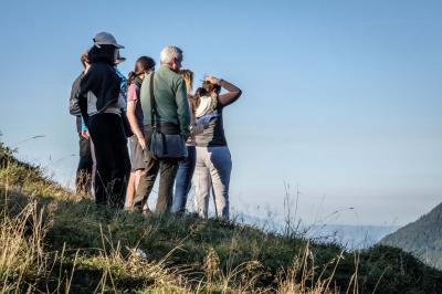 Groupe de personnes rassemblées en extérieur près de tentes et d'une table avec des verres, dans un cadre naturel.