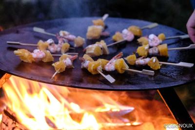 Groupe de personnes rassemblées en extérieur près de tentes et d'une table avec des verres, dans un cadre naturel.