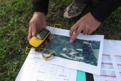Groupe de personnes rassemblées en extérieur près de tentes et d'une table avec des verres, dans un cadre naturel.