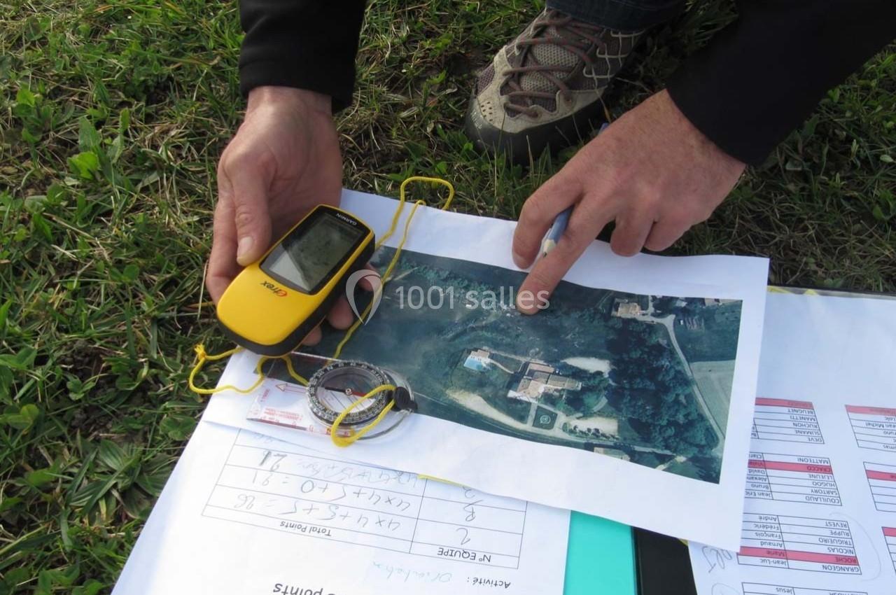 Une personne utilise un GPS portable et une carte aérienne pour analyser une zone sur le terrain.