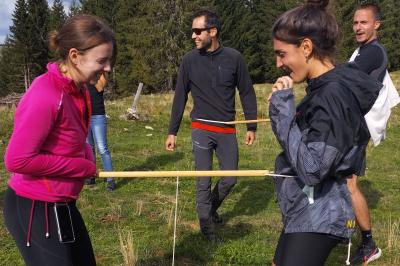 Groupe de personnes rassemblées en extérieur près de tentes et d'une table avec des verres, dans un cadre naturel.