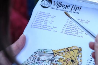 Groupe de personnes rassemblées en extérieur près de tentes et d'une table avec des verres, dans un cadre naturel.