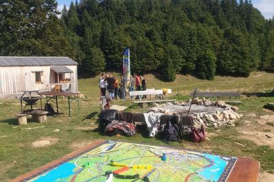 Groupe de personnes rassemblées en extérieur près de tentes et d'une table avec des verres, dans un cadre naturel.