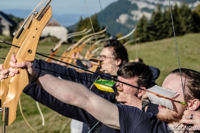 Groupe de personnes rassemblées en extérieur près de tentes et d'une table avec des verres, dans un cadre naturel.