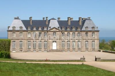 Chambre lumineuse avec lit à baldaquin, armoire à miroir, chaise en bois et rideaux rouges encadrant une fenêtre ouverte.