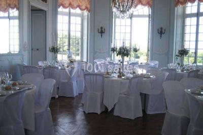 Chambre lumineuse avec lit à baldaquin, armoire à miroir, chaise en bois et rideaux rouges encadrant une fenêtre ouverte.