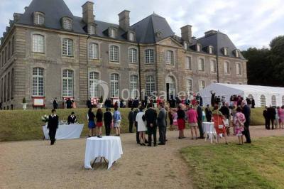 Chambre lumineuse avec lit à baldaquin, armoire à miroir, chaise en bois et rideaux rouges encadrant une fenêtre ouverte.