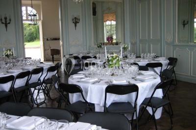 Chambre lumineuse avec lit à baldaquin, armoire à miroir, chaise en bois et rideaux rouges encadrant une fenêtre ouverte.