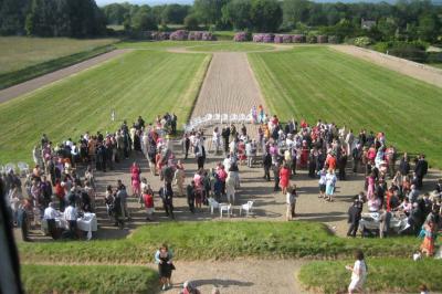 Chambre lumineuse avec lit à baldaquin, armoire à miroir, chaise en bois et rideaux rouges encadrant une fenêtre ouverte.