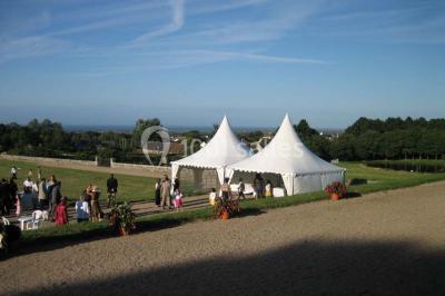 Chambre lumineuse avec lit à baldaquin, armoire à miroir, chaise en bois et rideaux rouges encadrant une fenêtre ouverte.