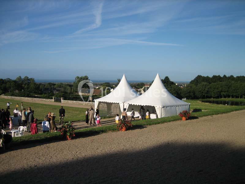Deux tentes blanches installées dans un champ, entourées de personnes lors d'un événement en plein air.
