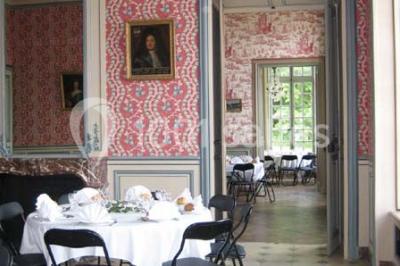 Chambre lumineuse avec lit à baldaquin, armoire à miroir, chaise en bois et rideaux rouges encadrant une fenêtre ouverte.