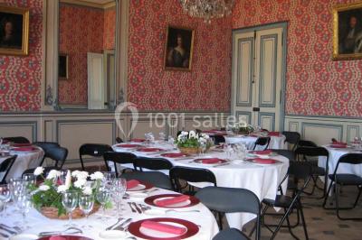 Vue d'un village avec des maisons entourées de verdure, un chemin en premier plan et la mer à l'horizon sous un ciel bleu.