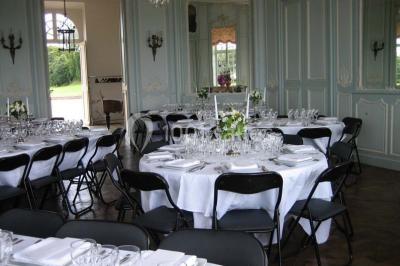 Vue d'un village avec des maisons entourées de verdure, un chemin en premier plan et la mer à l'horizon sous un ciel bleu.