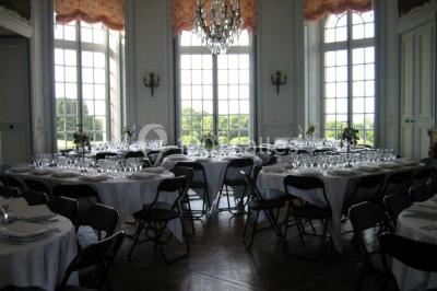 Vue d'un village avec des maisons entourées de verdure, un chemin en premier plan et la mer à l'horizon sous un ciel bleu.