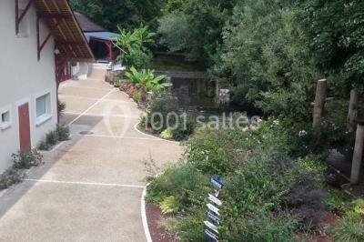 Miniature Location salle Onzain (Loir-et-Cher) - Le Manoir du Moulin #16 Vue depuis une terrasse rouge sur un petit cours d'eau bordé d'arbres, avec des maisons en arrière-plan.