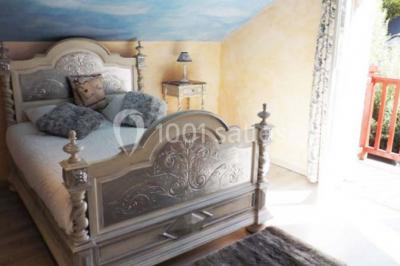 Miniature Location salle Onzain (Loir-et-Cher) - Le Manoir du Moulin #20 Vue depuis une terrasse rouge sur un petit cours d'eau bordé d'arbres, avec des maisons en arrière-plan.