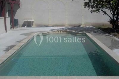 Miniature Location salle Onzain (Loir-et-Cher) - Le Manoir du Moulin #7 Vue depuis une terrasse rouge sur un petit cours d'eau bordé d'arbres, avec des maisons en arrière-plan.