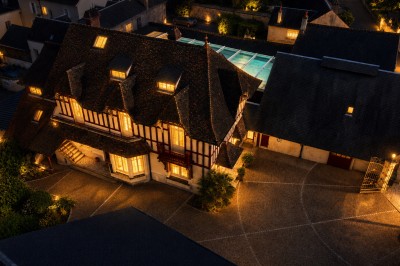 Vue depuis une terrasse rouge sur un petit cours d'eau bordé d'arbres, avec des maisons en arrière-plan.