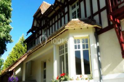 Miniature Location salle Onzain (Loir-et-Cher) - Le Manoir du Moulin #6 Vue depuis une terrasse rouge sur un petit cours d'eau bordé d'arbres, avec des maisons en arrière-plan.