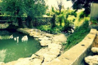 Miniature Location salle Onzain (Loir-et-Cher) - Le Manoir du Moulin #23 Vue depuis une terrasse rouge sur un petit cours d'eau bordé d'arbres, avec des maisons en arrière-plan.