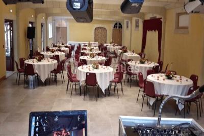 Miniature Location salle Onzain (Loir-et-Cher) - Le Manoir du Moulin #3 Vue depuis une terrasse rouge sur un petit cours d'eau bordé d'arbres, avec des maisons en arrière-plan.