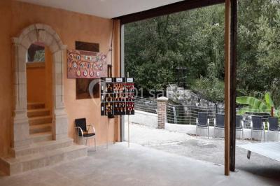 Miniature Location salle Onzain (Loir-et-Cher) - Le Manoir du Moulin #19 Vue depuis une terrasse rouge sur un petit cours d'eau bordé d'arbres, avec des maisons en arrière-plan.