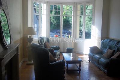 Miniature Location salle Onzain (Loir-et-Cher) - Le Manoir du Moulin #22 Vue depuis une terrasse rouge sur un petit cours d'eau bordé d'arbres, avec des maisons en arrière-plan.