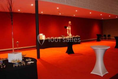 Vue intérieure d'un espace de loisirs avec sièges, tables, escalier central et décorations colorées sous un plafond haut.