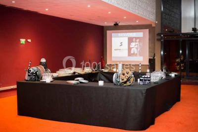 Vue intérieure d'un espace de loisirs avec sièges, tables, escalier central et décorations colorées sous un plafond haut.