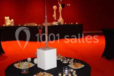 Vue intérieure d'un espace de loisirs avec sièges, tables, escalier central et décorations colorées sous un plafond haut.