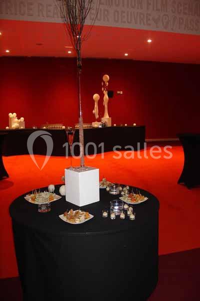 Table ronde avec des amuse-bouches variés, décorée d'un centre de table minimaliste, dans une salle à moquette rouge.