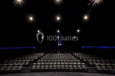 Vue intérieure d'un espace de loisirs avec sièges, tables, escalier central et décorations colorées sous un plafond haut.
