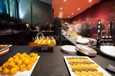 Vue intérieure d'un espace de loisirs avec sièges, tables, escalier central et décorations colorées sous un plafond haut.