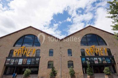 Vue intérieure d'un espace de loisirs avec sièges, tables, escalier central et décorations colorées sous un plafond haut.