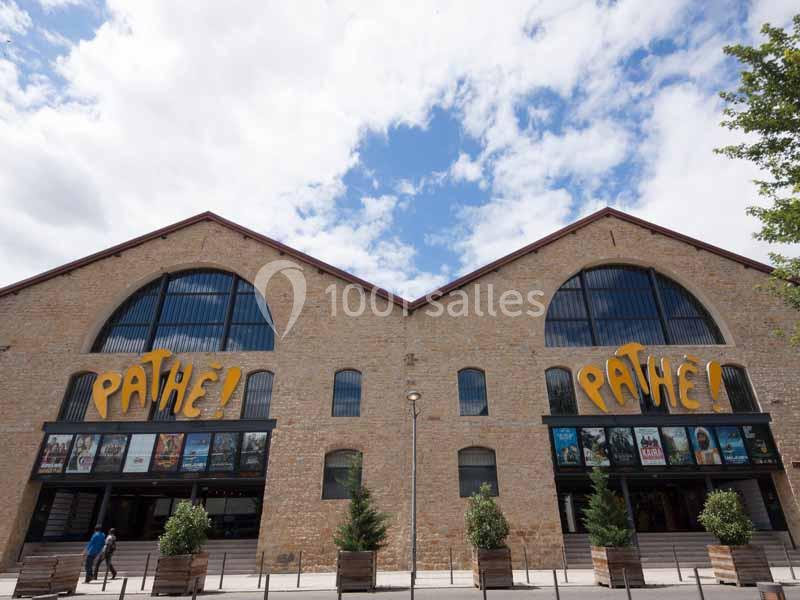 Façade en briques d'un cinéma Pathé avec affiches de films en vitrine, sous un ciel partiellement nuageux.