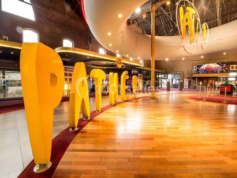 Ensemble de grandes lettres jaunes formant le mot ’Pathé’ dans le hall lumineux d'un cinéma moderne.