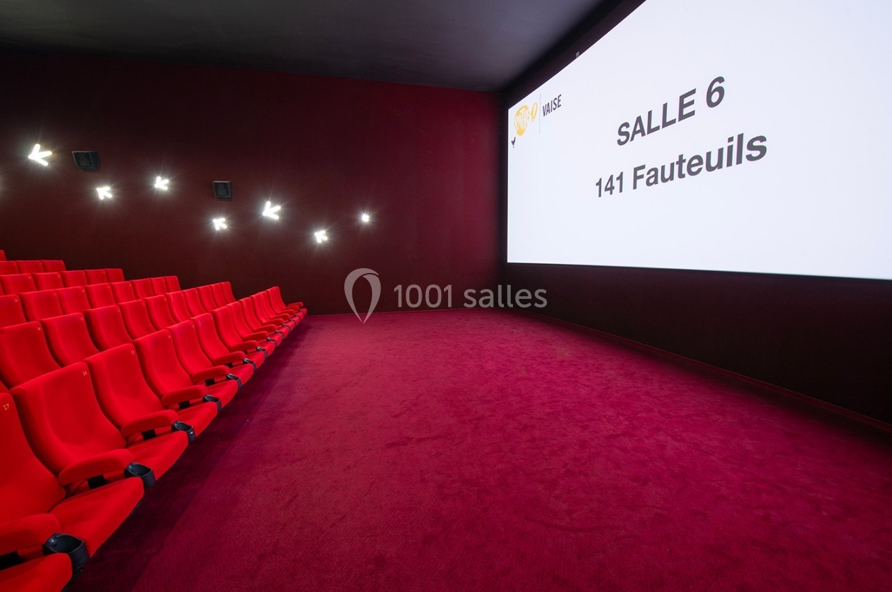 Salle de cinéma avec des fauteuils rouges, un écran affichant ’Salle 6, 141 fauteuils’ et un sol recouvert de moquette rouge.