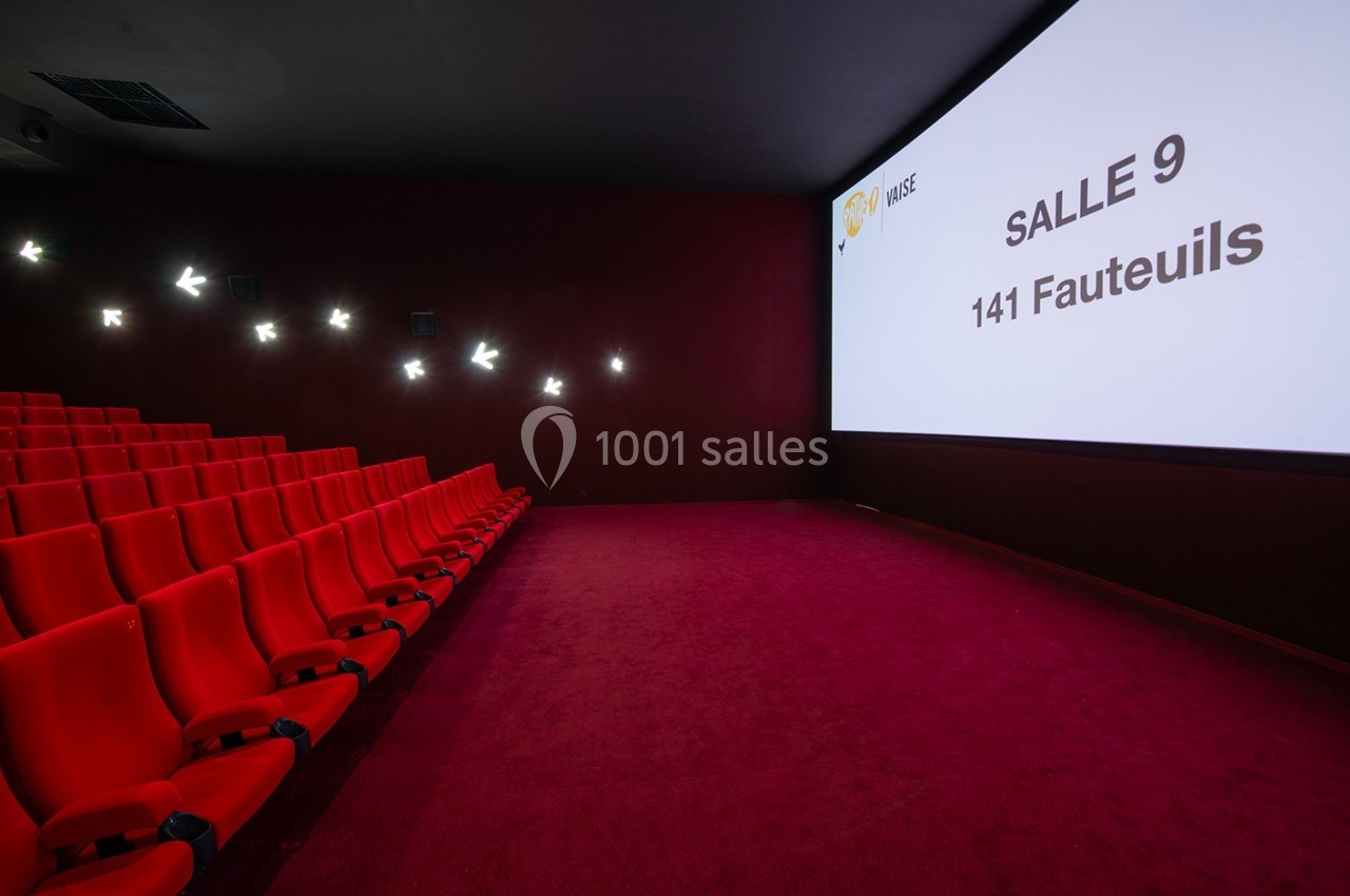 Salle de cinéma vide avec des rangées de fauteuils rouges et un écran affichant ’Salle 9, 141 fauteuils’.