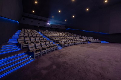Salle de cinéma avec des sièges rouges, un écran géant affichant ’Salle 14, 241 fauteuils’ et un éclairage tamisé.