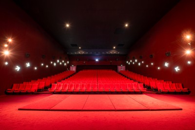 Salle de cinéma avec des sièges rouges, un écran géant affichant ’Salle 14, 241 fauteuils’ et un éclairage tamisé.