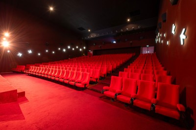 Salle de cinéma avec des sièges rouges, un écran géant affichant ’Salle 14, 241 fauteuils’ et un éclairage tamisé.