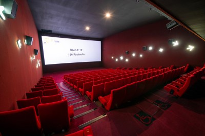 Salle de cinéma avec des sièges rouges, un écran géant affichant ’Salle 14, 241 fauteuils’ et un éclairage tamisé.