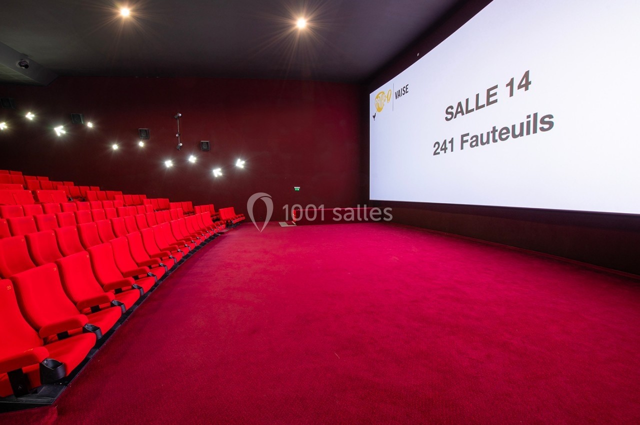 Salle de cinéma avec des sièges rouges, un écran géant affichant ’Salle 14, 241 fauteuils’ et un éclairage tamisé.
