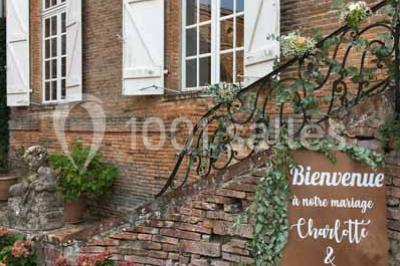 Église en briques rouges avec clocher-mur, entourée d'arbres et située dans un environnement rural.